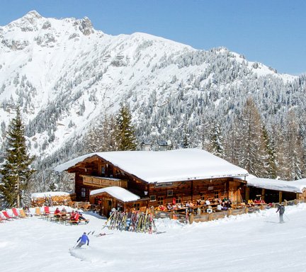Schneebedeckte Skihütte mit Bergpanorama im Hintergrund