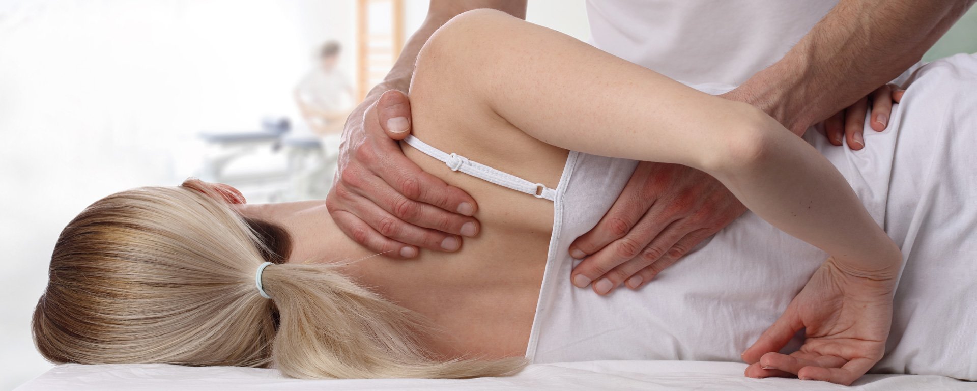 Physiotherapeut bei der Behandlung einer Patientin am Rücken