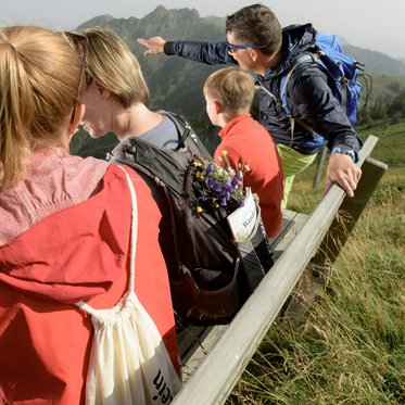 Familie mit Kindern auf einer Aussichtsbank an einem Wanderweg in den Bergen Gasteins